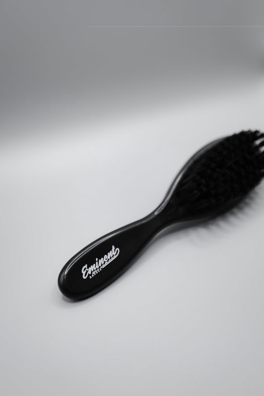 Black hairbrush with 'Eminent' branding on a white background